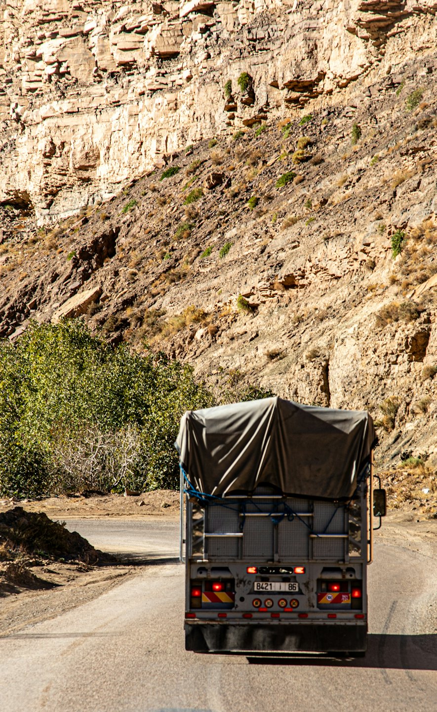 Cargo truck driving on a winding dirt mountain road.
