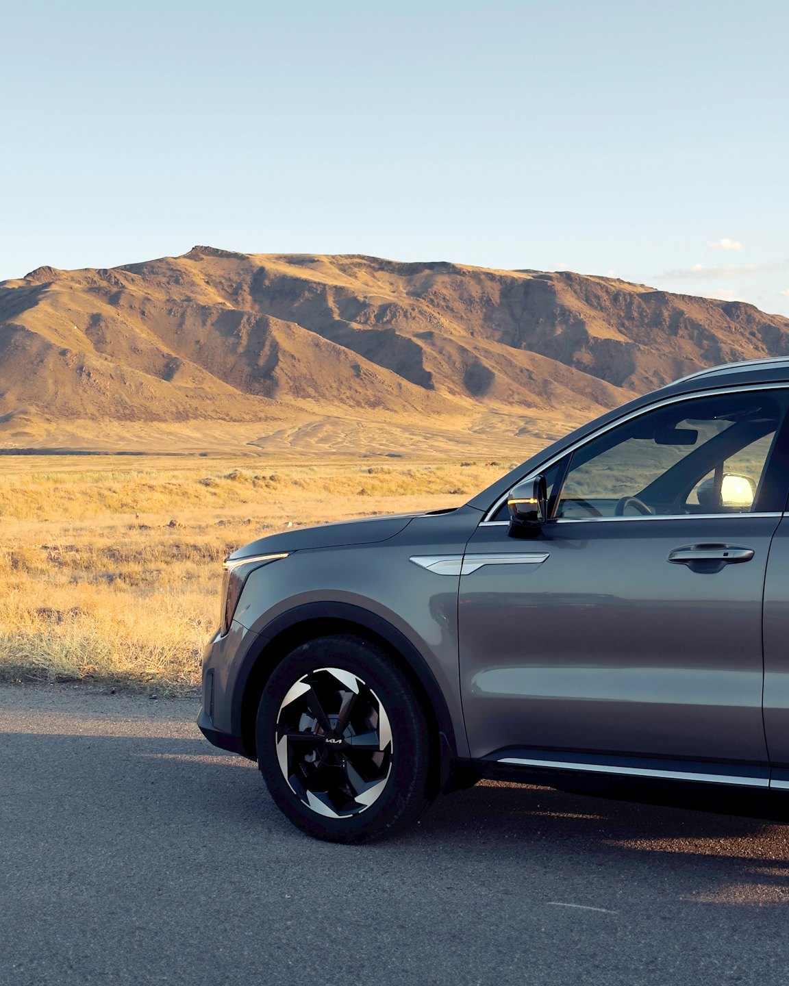 Grey modern SUV parked along a desert mountain road.
