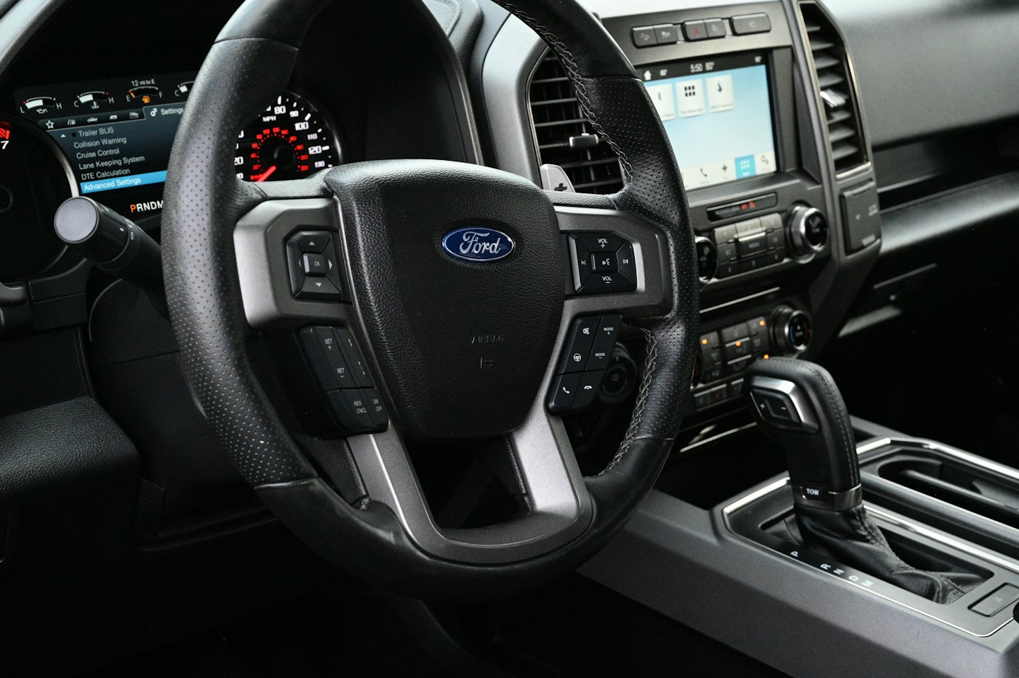 Modern car steering wheel with digital dashboard and infotainment screen.
