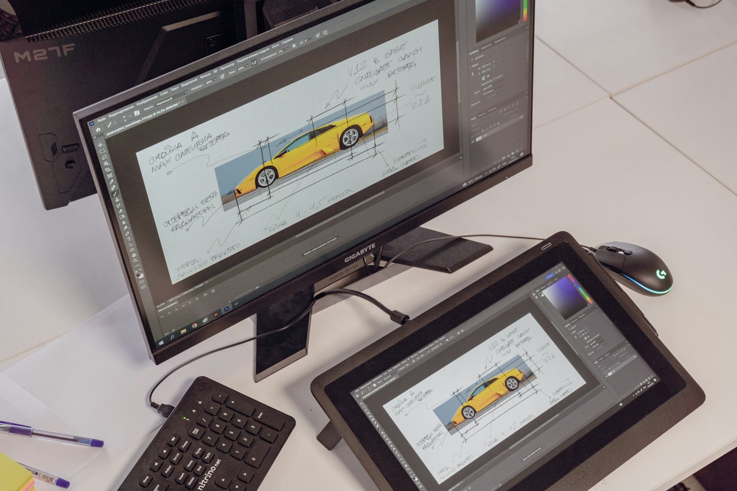Desk with computer, tablet, keyboard, mouse, and pens showing car design.